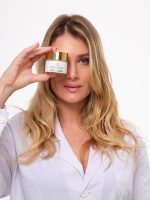 Mujer con camisa blanca mostrando la crema facial hidratante OROBORN